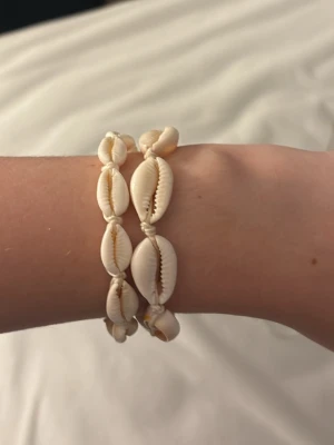 Vita snäckarmband  - Två vita snäckarmband, med snöre som justerar storleken, stilrent och jätte fint till semestern utomlands!🐚☀️