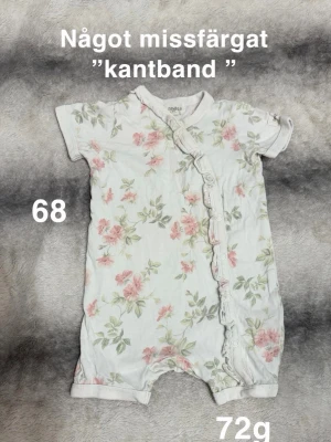 Blommig kortärmad pyjamas - Supersöt kortärmad pyjamas med blommigt mönster i rosa och grönt på vit botten.  med volangdetalj och tryckknappar framtill gör den enkel att ta på. Perfekt för mysiga nätter och chill dagar hemma.🌸Något missfärgad kantband. Storlek 68