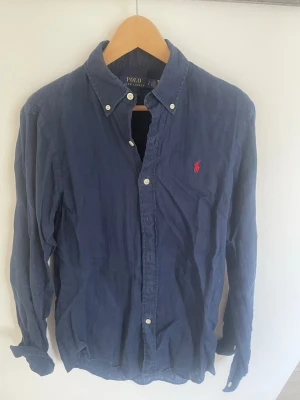 Ralph lauren linneskjorta - Säljer min mörkblåa Ralph Lauren linneskjorta i strlk S men  skulle också säga att den passar M (custom fit). Ett riktigt schysst plagg att ha från sen vår till tidig höst, passar till allt!