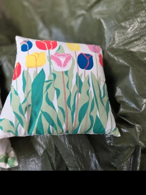 Svenskt Tenn Kuddar med färgglada tulpaner - Säljer en fyrkantig kudde med ett färgstarkt tulpanmönster i rött, gult, blått, rosa och grönt på vit botten. Kudden har ett lekfullt och vårigt tryck som livar upp vilket rum som helst. Perfekt som inredningsdetalj i soffan eller på sängen.  32×32 samt 29x 29 cm