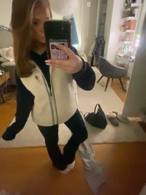 Patagonia väst  - Mysig vit fleeceväst från Patagonia med ljusgröna detaljer och dragkedja framtill. I storlek M men jag som i vanliga fall har Xs sitter den snyggt genom o vika upp massar även bra på en kille då min pojkvän använder min mest. Västen har två fickor med dragkedja och en liten logga på bröstet. Perfekt att slänga över en hoodie för extra värme.