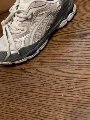 Vita och gråa acics gel - Snygga sneakers i vitt och grått med meshpaneler för extra ventilation och detaljer i mockaimitation. Skorna har en chunky sula och klassisk snörning. Perfekta för dig som gillar sportig stil och vill ha något bekvämt till vardags.