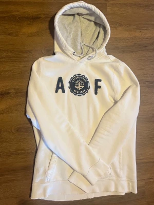 Vit Abercrombie & Fitch hoodie - Säljer denna vintage Abercrombie hoodien i ungefär storlek L. Släng iväg ett dm ifall du har nån fundering!