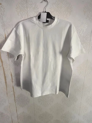 Vit basic t-shirt i bomull - Enkel och stilren vit t-shirt med rund hals och korta ärmar. Tillverkad i mjuk bomull för en skön känsla. Perfekt att matcha med jeans eller shorts för en clean look. Loose