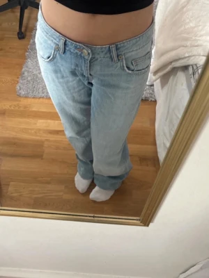 Blå baggy jeans  - Säljer ett par helt nya och oanvända ljusblå jeans med låg midja från zara i storlek 32. Jeansen har klassiska fem fickor, bälteshällor och stängs med knapp och dragkedja. Perfekta för en avslappnad och trendig look.