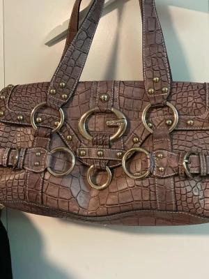 Lila väska   - Säljer en väldigt fin väska som inte har kommit till någon användning, köpte den secondhand så vet inte exakt vart den är ifrån men jag tycker det ser ut som det står guess på den , men kan vara fel. Skulle säga att den är som ny, inga slutningar/ fläckar jätte fin väska verkligen. Den har silverdetaljer om det är svårt att se på bilden 💕mått: ca 17 cm hög och ca 33 cm bred. Du kan ha den på axeln/ i handen 