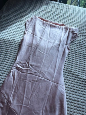 Ljusrosa långklänning i satin -  fin rosa satin klänning som är of shoulder och har en lite tajtare överdel jämfört med underdel som jag skulle säga är lite utsvängt. Säljer den då jag beställde den för balen men valde att ha en annan färg så den är helt oanvänd. 