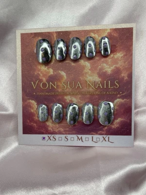 Pluto (XS);ExtraShortAlmond  - Handgjorda press-on naglar i silver med lila prickar. Naglarna har en extra kort oval form och kommer i storlek XS: 14 mm, 11 mm, 11,5 mm, 10 mm, 8 mm. Perfekt för dig som vill ha ett unikt och kreativt nagelset.