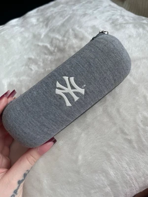 Grått NY solglasögonfodral - Snyggt grått solglasögonfodral med New York Yankees-logga i vitt. Knappt använd!