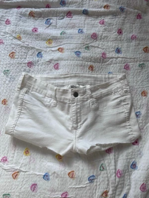 Vita lågmidjade shorts - Snygga vita korta jeansshorts som är så snygga på! Shortsen har knapp och dragkedja framtill samt bälteshällor. Perfekta för varma dagar och enkel att matcha med allt.
