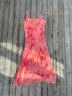 Rosa klänning - Fin rosa klänning perfekt för sena sommarkvällar eller i höst med en stickad tröja över. Blommigt mönster och med smala axelband. 
