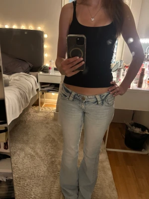 Ljusblå bootcut jeans från Gina 14+ - Säljer ett par ljusblå bootcut jeans med låg midja och snygg broderad detalj på bakfickorna. Säljer då de e för långa för mig, därför e de lite slitna vid fötterna💗