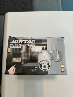 Jortan WiFi Övervakningskamera utomhus/inomhus – Ny i förpackning - Säljer en Jortan fullfärg smartkamera med WiFi-anslutning. Kameran har två antenner, rund form och är vit. Den stödjer rörelsedetektering, tvåvägsljud och kan styras via app till PC, iPad och mobil. Perfekt för övervakning både inomhus och utomhus.