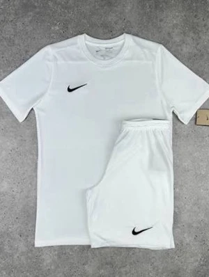 Vitt träningsset från Nike - Säljer ett fräscht vitt träningsset från Nike med t-shirt och shorts. Båda plaggen har den klassiska svarta Nike-loggan. Perfekt för gymmet eller fotbollsträningen. Materialet är lätt och andas, vilket gör det bekvämt under intensiva pass.