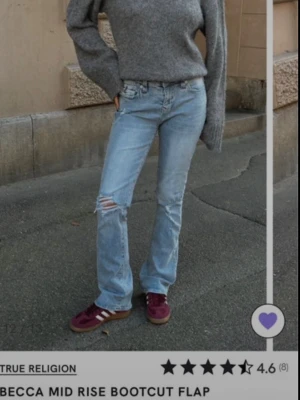 True Religion ljusblå bootcut jeans - Säljer ett par ljusblå bootcut jeans från True Religion med slitningar på ena knät och ikonisk fickdesign med röd söm. Ny med prislapp. Jeansen har normal midja och klassisk femficksmodell. Perfekta för en avslappnad och trendig look.Nypris 1299kr