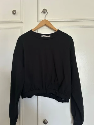 Svart sweatshirt - En enkel svart sweatshirt med rund hals och långa ärmar. Tröjan har resår i midjan för en avslappnad och trendig look. Perfekt att matcha med höga jeans eller mjukisbyxor. Materialet känns mjukt och bekvämt mot huden. OBS! tröjan är märkt med storlek L men är felmärkt så egentligen en S/M🩷