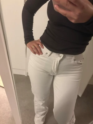Vita raka jeans med hög midja - Säljer ett par vita jeans med rak passform och hög midja. Klassisk femficksmodell med knapp- och dragkedjegylf. Jeansen har en stilren look och är perfekta för dig som vill ha en clean och fräsch stil. Materialet är kraftigt denim i bomull.
