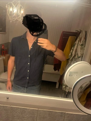 Mörkblå kortärmad skjorta - Snygg mörkblå skjorta med korta ärmar och vita knappar framtill. Skjortan har en klassisk krage och rak passform, perfekt till jeans eller shorts. Tillverkad i ett lätt och bekvämt material som passar bra till varma dagar.