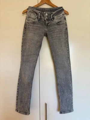 Grå tvättade LTB lowrise jeans modell Jonguil storlek 25/30 - Säljer ett par grymt snygga grå LTB jeans med låg midja tvättad och dubbla knappar i midjan. Jeansen har fem fickor och är gjorda i stretchigt denimtyg. Storlek 25/30