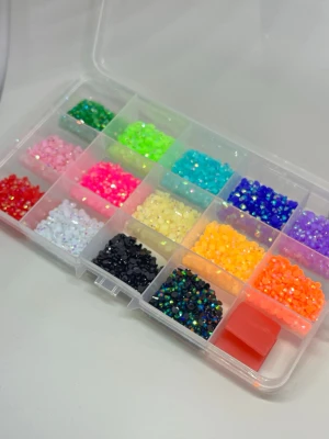 Bedazzel kit med strass och verktyg - Ett komplett nageldekoration kit med färgglada strasstenar i olika former och storlekar, pincett, vaxpenna och lim. Perfekt för att skapa kreativa och unika nageldesigner. Kommer i en praktisk förvaringslåda med flera fack för enkel sortering.
