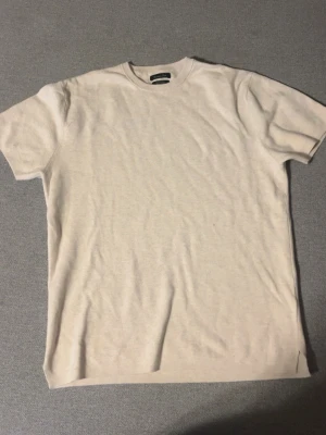 Beige Massimo dutti T-shirt  - En enkel Massimo dutti beige t-shirt i mjuk bomull. T-shirten har rund halsringning och korta ärmar, perfekt för en clean och avslappnad look. Passar till det mesta och är ett måste i garderoben.