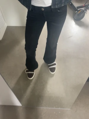 Svarta bootcut jeans - Snygga svarta bootcut jeans med klassisk femficksmodell och normal midja. Jeansen har en lätt utsvängd passform nedtill och stängs med knapp och dragkedja. Perfekta till sneakers eller boots för en avslappnad look.