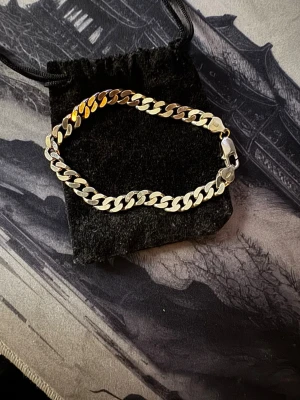 Kedjearmband i silverfärg - Snyggt kedjearmband i silverfärgad metall med platta, breda länkar. Armbandet har en klassisk karbinhake och en stilren design som passar till många olika looks. Perfekt accessoar för dig som gillar minimalistisk och tidlös stil.