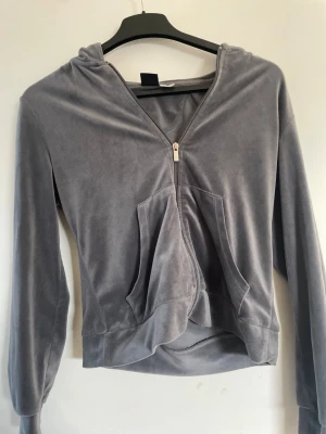 Grå velourhoodie från Gina Tricot - Mjuk och skön grå hoodie i velour från Gina Tricot. Hoodien har dragkedja framtill, två stora fickor och en klassisk huva. 
