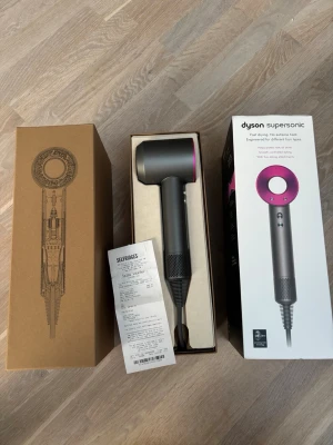 Dyson Supersonic hårfön grå/rosa - Säljer en Dyson Supersonic hårfön i snygg grå och rosa färg. Kommer i originalförpackning med modern design och smart teknik som skyddar håret mot extrem värme. Perfekt för dig som vill ha snabb och skonsam hårtorkning med stilren look.