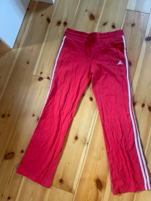 Röda Adidas mjukisbyxor med vita ränder - Rosa adidasbyxor midwaist och bootcut!! Supersnygga men kom inte till användning för min dansstil jag dansat! Passar till cool y2k outfit eller bara till idrott eller vardags!!