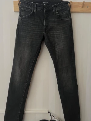 Svarta slim fit jeans från Jack & Jones - Snygga svarta slim fit jeans från Jack & Jones med klassisk femficksmodell. Jeansen har normal midja och raka ben, perfekta till en avslappnad stil. Tillverkade i stretchigt denim för extra komfort. Storlek 28/32