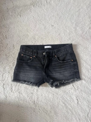 Svarta jeansshorts  - Säljer ett par svarta jeansshorts med fransig kant och klassisk femficksdesign. Shortsen har knapp och dragkedja framtill. Köpte på plick men har aldrig använt förra säljaren hade använt shortsen. Skriv för mer info🤍