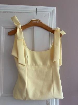 Slutsåld Zara topp - Söt ljusgul topp med breda axelband som knyts i rosetter. Toppen har en rak passform och fyrkantig urringning, perfekt för en somrig look. Materialet känns mjukt och lätt, vilket gör den bekväm att bära. Storleken är s men funkar både för s och xs.
