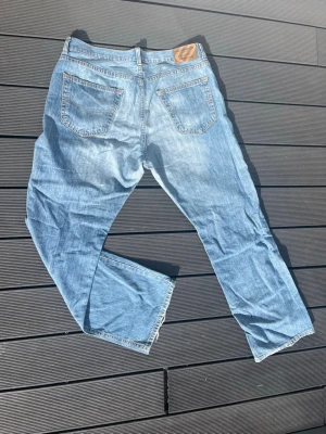 Ljusblå bootcut jeans - Säljer ett par ljusblå jeans med bootcut passform och klassisk femficksdesign. Jeansen har normal midja och är tillverkade i denim med lätt slitna detaljer. Perfekta för en avslappnad och trendig look.