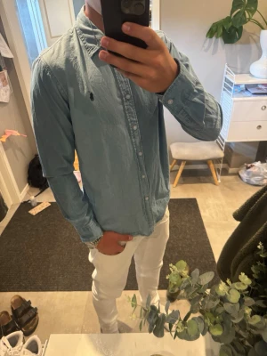 Ljusblå ralphlauren skjorta - Snygg ljusblå ralph lauren skjorta skjortan är i nästan lite jeansmaterial och väldigt snygg storlek m passar mig bra runt 188cm och 75kg