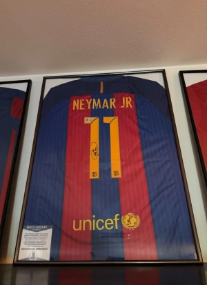 En 100% äkta NEYMAR JR signerad FC Barcelona matchtröja + Beckett äktenhetsbevis - Hej säljer:  En av mina främsta juveler i min autograf samling.. En 100% äkta Neymar Jr signerad FC Barcelona  matchtröja + Beckett Äktenhetsbevis. Champions League patches på armarna).  Äktenhetsbeviset är från Beckett och har ett unikt serienummer/QR-kod som man kan söka fram på Becketts hemsida och som styrker/bevisar autografens äkthet.  Obs tavelramen ingår ej! Vanlig 50x70 ram finns att köpa överallt.   Tröjan är köpt för 12 000kr.. Värderad till 15-20 000kr.. Säljs för endast 8999kr…