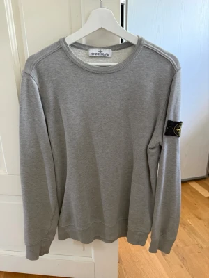 Grå sweatshirt från Stone Island - Snygg grå sweatshirt från Stone Island med klassisk rund halsringning och ikonisk logo. Tillverkad i mjukt bomullsmaterial. Storlek S