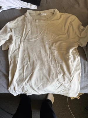 Beige t-shirt från Zara - En enkel och stilren beige t-shirt från Zara i mjuk bomull. Klassisk rund halsringning och korta ärmar. Perfekt basplagg att matcha med allt i garderoben.