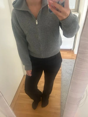 Grå zip hoodie med huva - Säljer en enkel och stilren grå hoodie med dragkedja framtill och huva. Hoodien har ribbade muddar vid ärmslut och nederkant samt två fickor framtill. Perfekt för en avslappnad och bekväm look. Sitter som xs/s