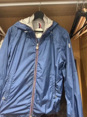 Moncler windbreaker - Riktigt snygg Moncler-urville windbreaker i blått. Perfekt för hösten och fungerar även utmärkt under vår/sommar. Jackan är använd men fortfarande i bra skick. Det finns några mindre synliga tecken på användning. De två sista bilderna visar de defekter som finns på jackan.  Storlek S. Bilder på detaljer och äkthetsmärkning finns i annonsen.  Säljes till ett bra pris med hänsyn till skicket. Hör gärna av er vid frågor!