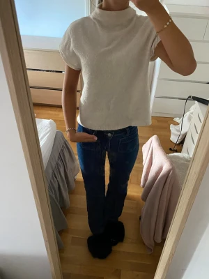 Vit stickad polotopp - Säljer en vit stickad polotopp med korta ärmar och hög krage. 
