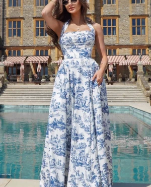 Vit långklänning med blått mönster - Elegant långklänning i vitt med blått blommigt mönster. Klänningen har halterneck, markerad midja och vid kjol som ger en romantisk siluett. Perfekt för sommarens alla tillfällen och ger en lyxig känsla med sitt klassiska tryck.