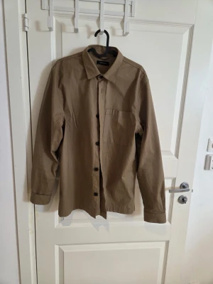 Beige skjorta från Matinique L - Säljer en stilren beige skjorta från Matinique i storlek L. Skjortan har klassisk krage, bröstficka och knappar framtill. Tillverkad i mjuk bomull och passar perfekt till en avslappnad men snygg look.