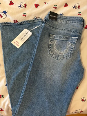 True religion Tilda Törnquist collab (crystals) - Säljer ett par ljusblå bootcut jeans från True Religion med snygga strassdetaljer på bakfickorna. Jeansen har klassisk femficksmodell och är tillverkade i mjuk denim. Dom är från Tilda Törnquist colab och säljer pga de är lite stora. Dom är 1500 så jag har get 400 kr rabatt 🥰🥰