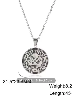 Silverfärgat halsband med Palestina-mynt - Snyggt halsband i silverfärgad metall med ett runt hängsmycke som liknar ett palestinskt mynt. Hängsmycket har texten 'Palestine' och årtalen 1955 och 1950, samt dekorativa detaljer och arabiska tecken. Kedjan är tunn och stilren.
