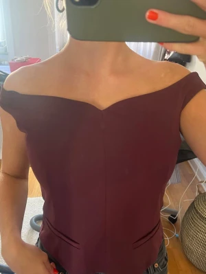 Vinröd offshoulder topp - Snygg vinröd topp med offshoulder-design och figurnära passform. Toppen har en hjärtformad urringning och är helt ärmlös, vilket ger en elegant och modern look. Perfekt att styla med jeans eller kjol för en trendig outfit.