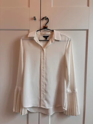 GANT vit skjorta / blus - Skjorta från GANT med plisserad ärm i stl 34 men skulle säga att den passar mer som stl 36. Jag har brukar ha 38 och den passar på mig men är lite tight över ryggen. Suuuperfin skjorta som inte kommer till användning och har använts sparsamt. Någon enstaka noppra som syns i vissa ljus (bild 5) och en antydan till liten färgskiftning på höger ärm (bild 6)