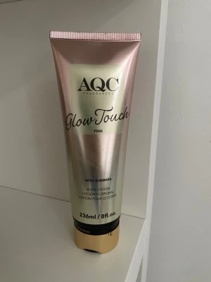 AQC Glow Touch Pink Body Lotion - AQC Glow Touch Pink är en kroppslotion med shimmer som ger huden en glansig finish. Tuben är skimrande rosa och guld med svart text och rymmer 236 ml. Perfekt för dig som vill ha extra lyster till huden.