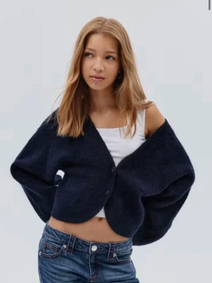 Mörkblå fluffig kofta med v-ringning - Mysig blå kofta med v-ringning och två knappar framtill. Koftan har en fluffig textur och är något croppad i modellen. Perfekt att slänga över en t-shirt eller linne för en chill look.