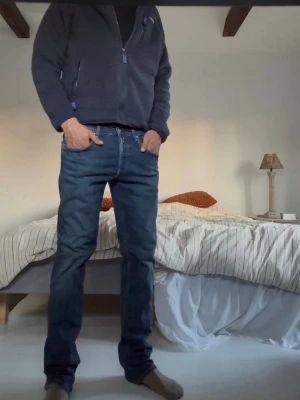 Replay groover - Säljer ett par mörkblå jeans med rak passform och klassiska fem fickor. Jeansen har en snygg tvätt och subtila slitningar för en avslappnad look. Tillverkade i denim med normal midja och dragkedjegylf. Från replay!